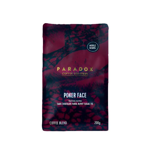Roasted coffee beans from The Roast Collective. Paradox Coffee Roasters, Poker Face Blend. Image shows a 200g bag of the coffee against a white background. The bag is two-tone in colour, with midnight blue and maroon arranged in a reptile skin pattern. Paradox's logo is centred in the top half of the bag, with the blend name, tasting notes and weight underneath.
