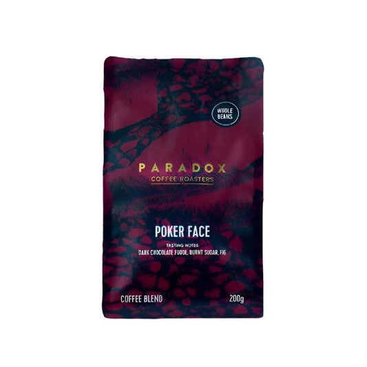 Roasted coffee beans from The Roast Collective. Paradox Coffee Roasters, Poker Face Blend. Image shows a 200g bag of the coffee against a white background. The bag is two-tone in colour, with midnight blue and maroon arranged in a reptile skin pattern. Paradox's logo is centred in the top half of the bag, with the blend name, tasting notes and weight underneath.