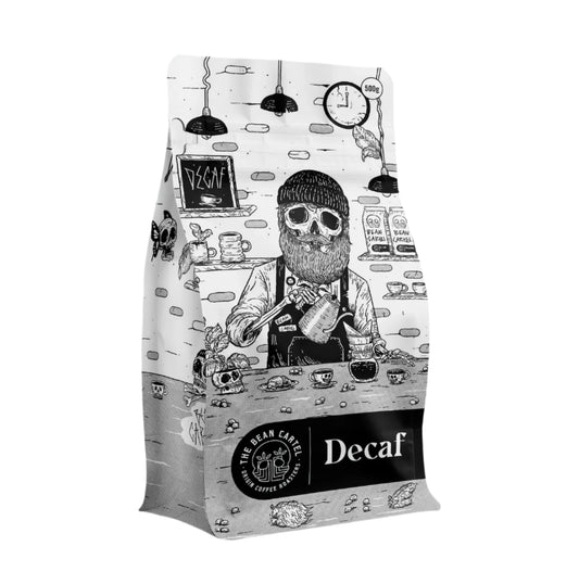 The Roast Collective. The Bean Cartel's Decaf coffee 500g bag with a stylized illustration of a barista and coffee-themed graphics against a white background.