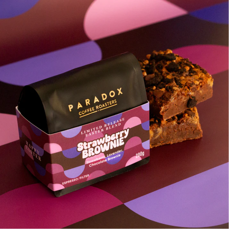 Paradox Coffee Roasters Strawberry Brownie coffee package with a brownie on a colorful background