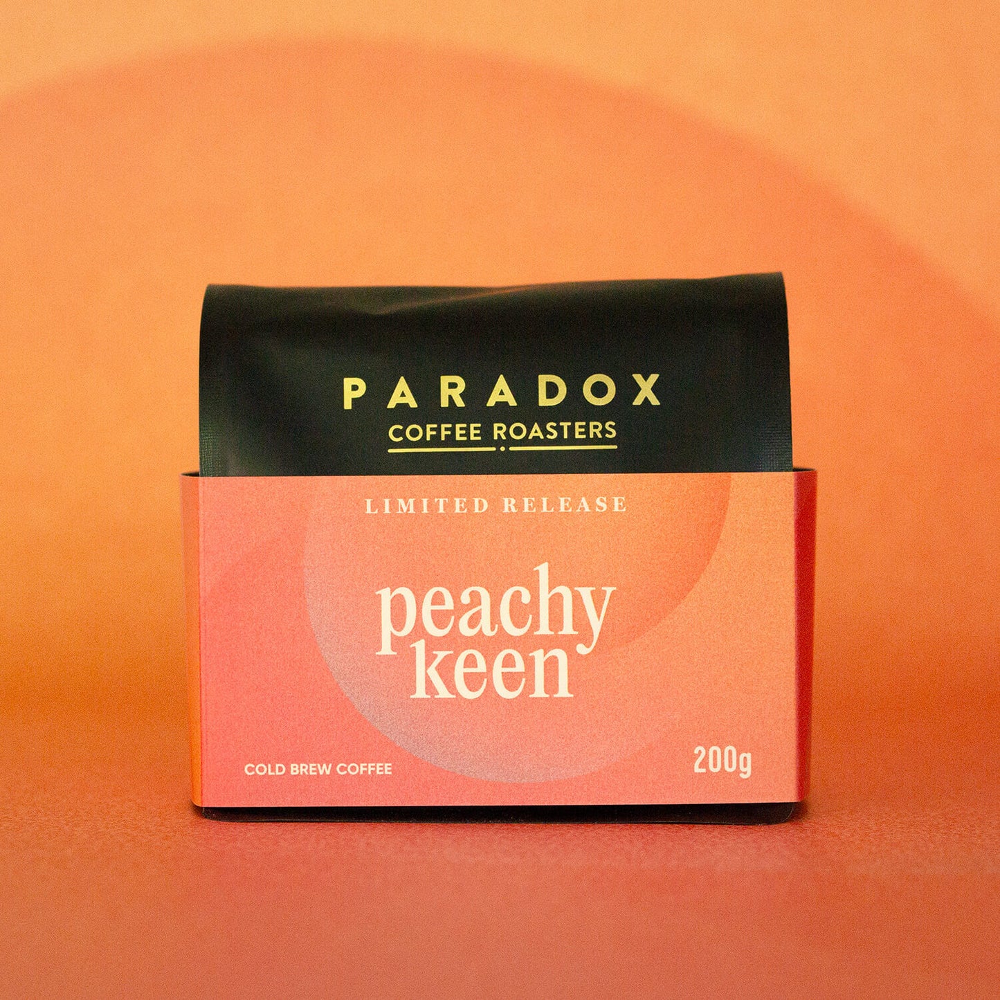 Roasted coffee beans Paradox Coffee Roasters Limited Edition: Peachy Keen 200g bag Cold Brew Coffee. Peach and orange coloured background. The Roast Collective.