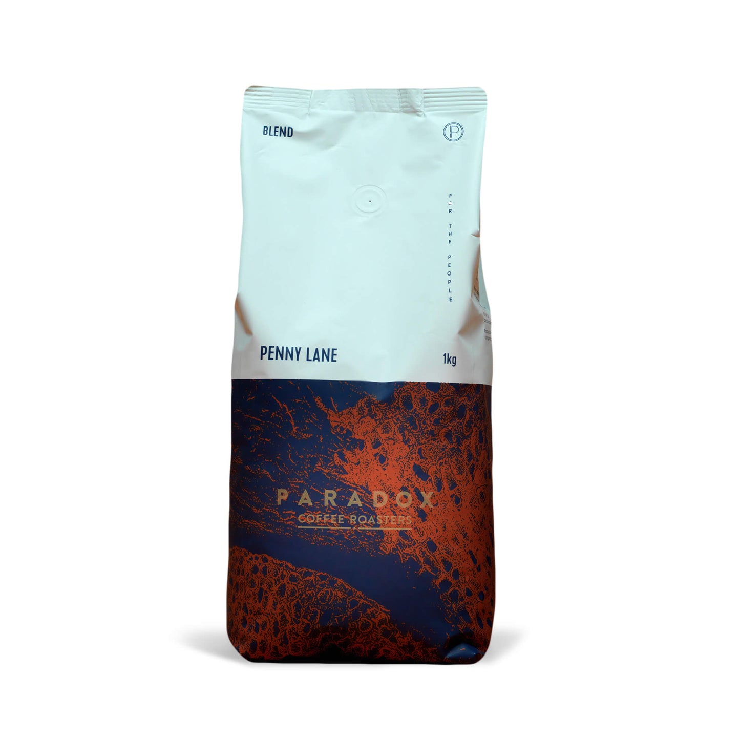 Roasted coffee beans from The Roast Collective. Paradox Coffee Roasters, Penny Lane Blend. Image shows a tri-tone 1kg bag of the coffee against a white background. The top half of the bag is white, with a navy blue and rust red pattern covering the bottom half of the bag. Paradox's logo is centred in the bottom half of the bag, with the lend name and weight at the bottom of the white section of the bag. 