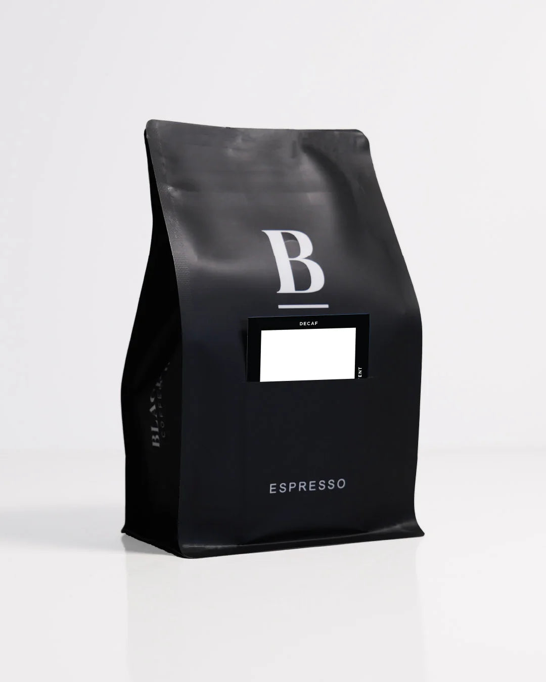 Roasted coffee beans. Blackboard Coffee Roasters, Blackboard Single Origin Decaf. Image shows a black 250g bag against a white background. The bag features the Blackboard logo and a pouch on the front with a product information card poking out. The Roast Collective.