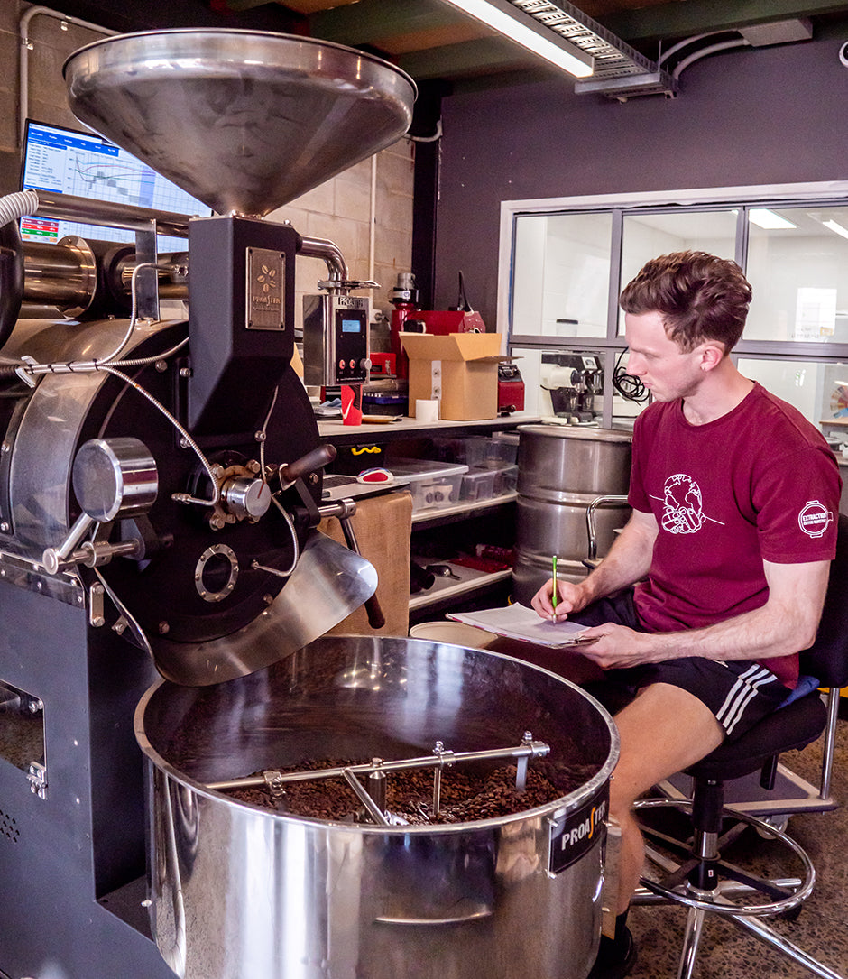 Person roasting coffee sitting at a coffee roasting machine
