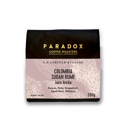 Roasted coffee beans. Paradox Coffee Roasters, Colombia - Sudan Rume anaerobic natural, produced by Jairo Arcila. Filter roast only. Image shows a 200g bag against a white background. The Roast Collective.